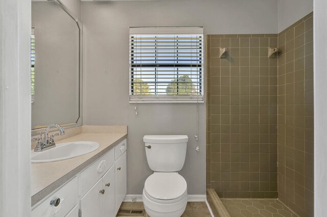 bathroom featuring a tile shower, tile patterned flooring, vanity, and toilet