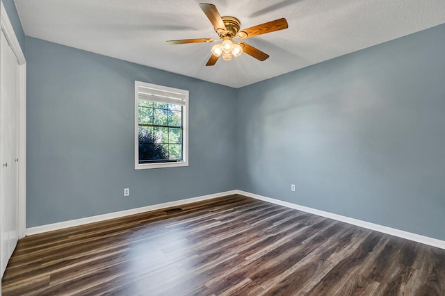 spare room featuring ceiling fan, dark wood-type flooring, and a textured ceiling