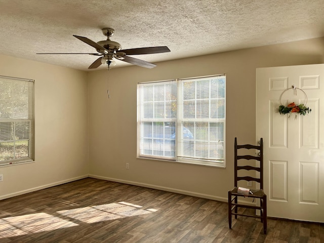 empty room with ceiling fan, dark hardwood / wood-style flooring, and a textured ceiling