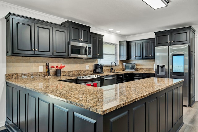 kitchen with light stone counters, sink, stainless steel appliances, and kitchen peninsula