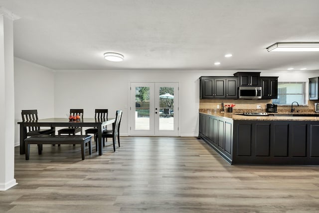 kitchen with ornamental molding, a healthy amount of sunlight, light hardwood / wood-style floors, and french doors