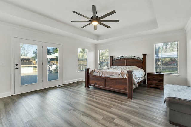 bedroom with crown molding, ceiling fan, access to exterior, wood-type flooring, and a raised ceiling