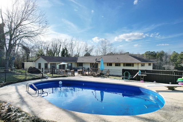 view of swimming pool featuring a diving board and a patio