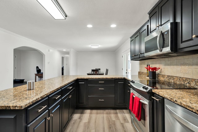 kitchen with stainless steel appliances, light wood-type flooring, and kitchen peninsula