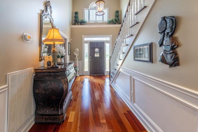 entrance foyer with visible vents, stairs, a wainscoted wall, and wood finished floors