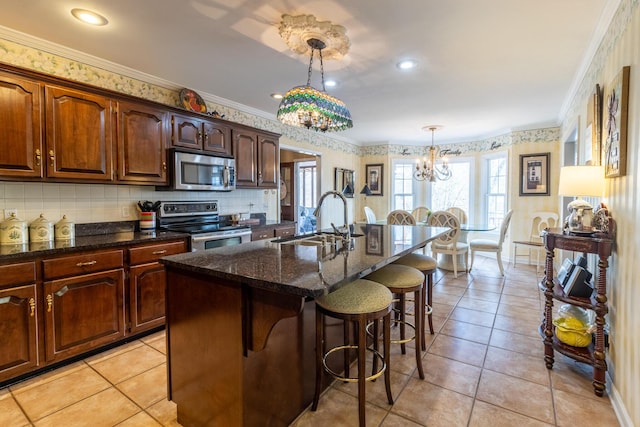 kitchen with an inviting chandelier, a sink, ornamental molding, stainless steel appliances, and a kitchen breakfast bar