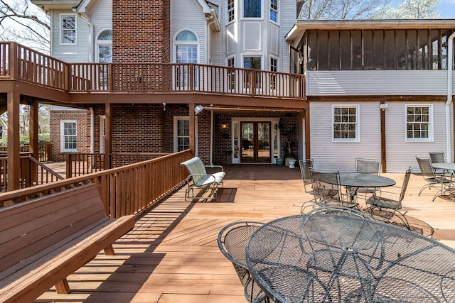 wooden deck with outdoor dining space, french doors, and a sunroom