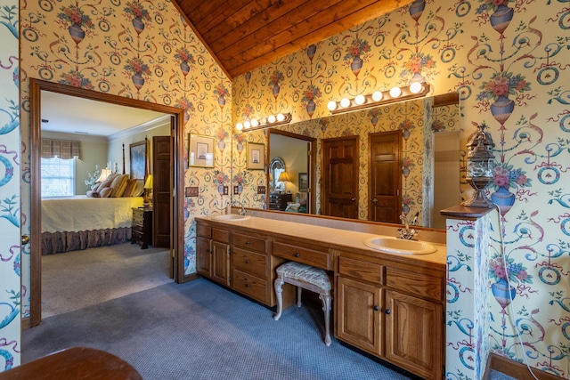 ensuite bathroom with wallpapered walls, ensuite bath, a sink, and vaulted ceiling