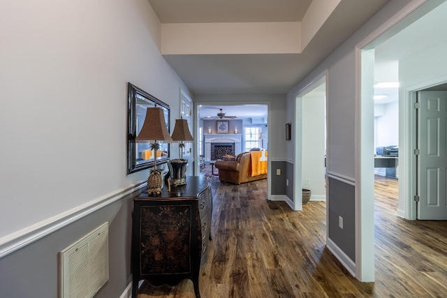 hall featuring wood finished floors, visible vents, and baseboards
