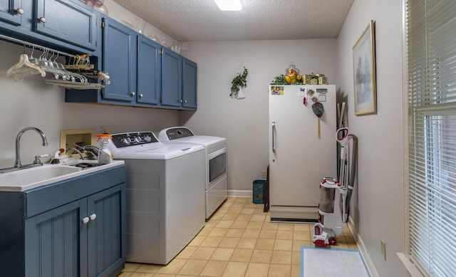 clothes washing area featuring light tile patterned floors, cabinet space, a textured ceiling, independent washer and dryer, and a sink
