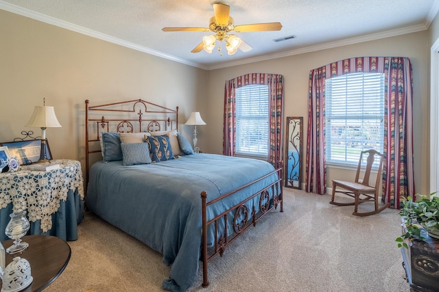 carpeted bedroom with visible vents, a textured ceiling, ornamental molding, and a ceiling fan