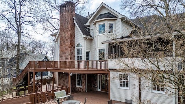 back of property with a chimney, a deck, and a shingled roof