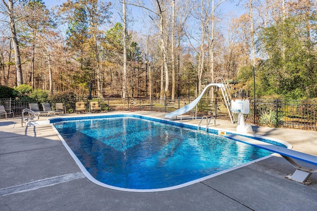 view of pool featuring a diving board, a patio area, and a water slide