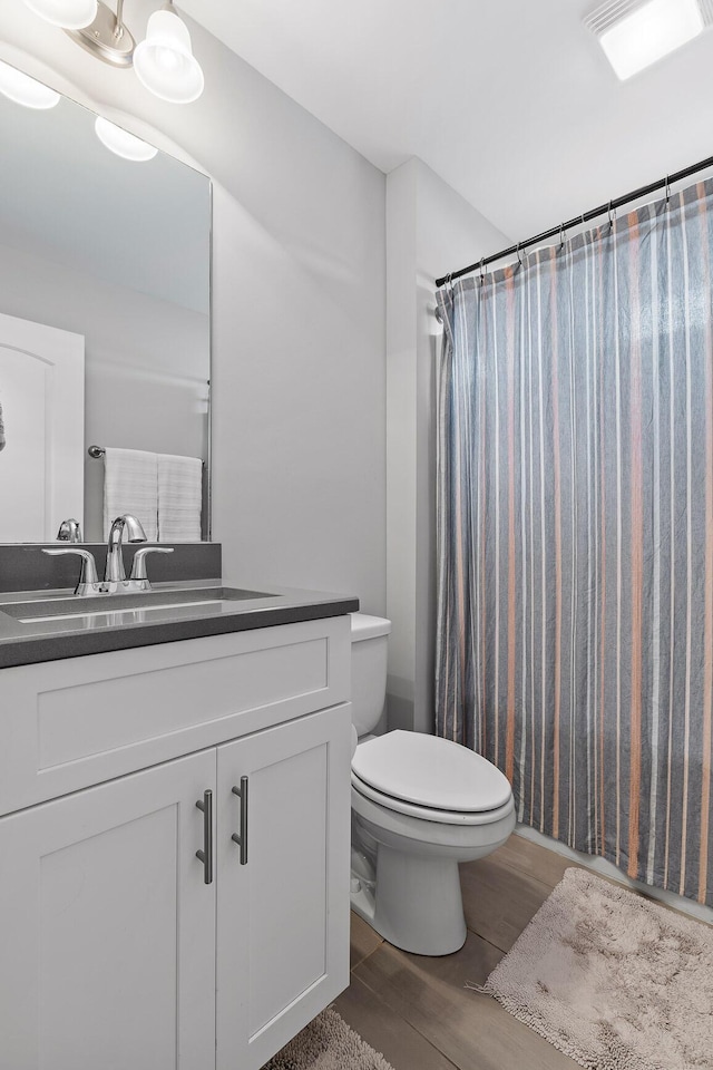 bathroom featuring toilet, vanity, a shower with shower curtain, and hardwood / wood-style flooring