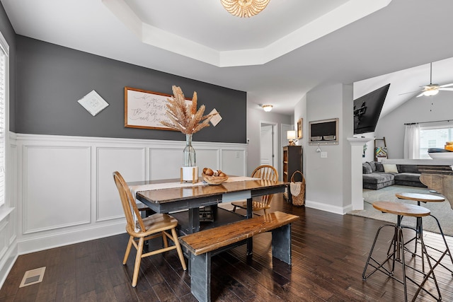 dining room with dark hardwood / wood-style floors, ceiling fan, and a raised ceiling