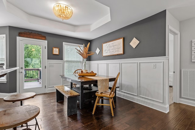 dining room with a raised ceiling and dark wood-type flooring