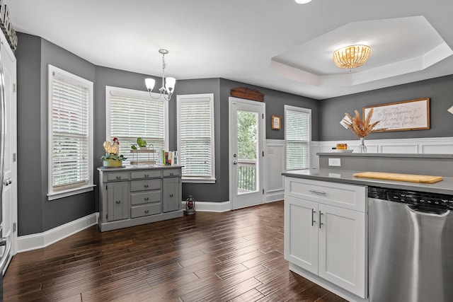 kitchen with a raised ceiling, stainless steel dishwasher, a chandelier, decorative light fixtures, and white cabinets