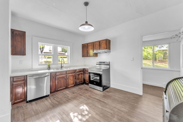 kitchen with plenty of natural light, stainless steel appliances, decorative light fixtures, and sink