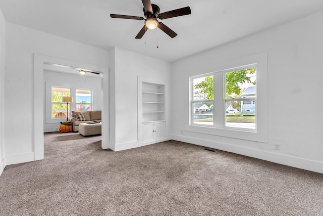 interior space with built in shelves, a wealth of natural light, and ceiling fan