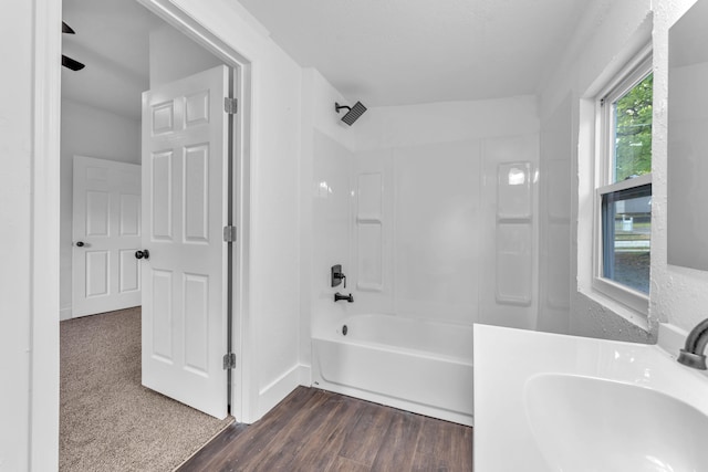 bathroom with washtub / shower combination, wood-type flooring, and sink