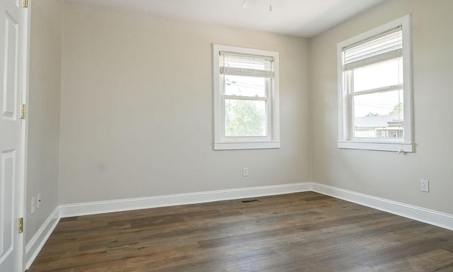 spare room with baseboards and dark wood-style floors