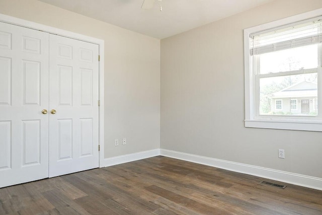 unfurnished bedroom featuring baseboards, dark wood-style floors, visible vents, and a closet