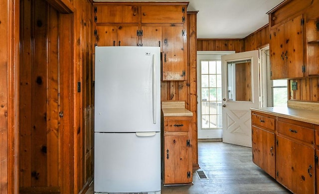 kitchen featuring freestanding refrigerator, a wealth of natural light, and brown cabinets