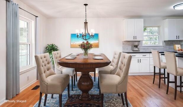 dining space with a notable chandelier and light hardwood / wood-style flooring