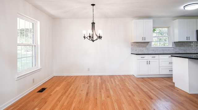 kitchen featuring white cabinets, light hardwood / wood-style flooring, decorative light fixtures, and decorative backsplash