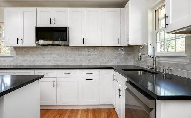 kitchen with white cabinets, tasteful backsplash, dishwasher, and sink