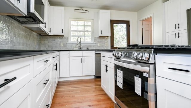 kitchen with sink, white cabinetry, tasteful backsplash, light hardwood / wood-style flooring, and appliances with stainless steel finishes