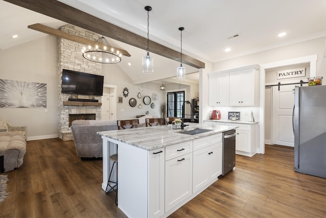 kitchen with open floor plan, vaulted ceiling with beams, a sink, and appliances with stainless steel finishes