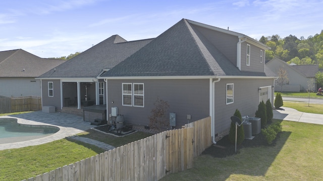 rear view of house with a fenced in pool, a shingled roof, a fenced backyard, a patio area, and a lawn