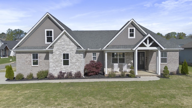 craftsman-style house with stone siding, a shingled roof, a porch, and a front yard