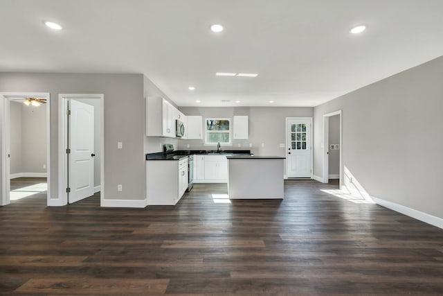 kitchen with ceiling fan, appliances with stainless steel finishes, a kitchen island, dark hardwood / wood-style flooring, and white cabinetry