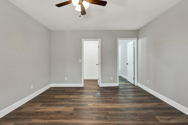 unfurnished bedroom with a walk in closet, ceiling fan, and dark wood-type flooring