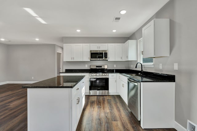 kitchen with dark wood-type flooring, white cabinets, sink, a kitchen island, and stainless steel appliances