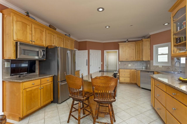 kitchen with appliances with stainless steel finishes, sink, ornamental molding, light tile patterned floors, and light stone counters