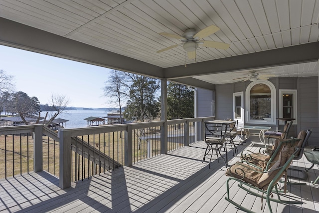 wooden deck with ceiling fan and a water view