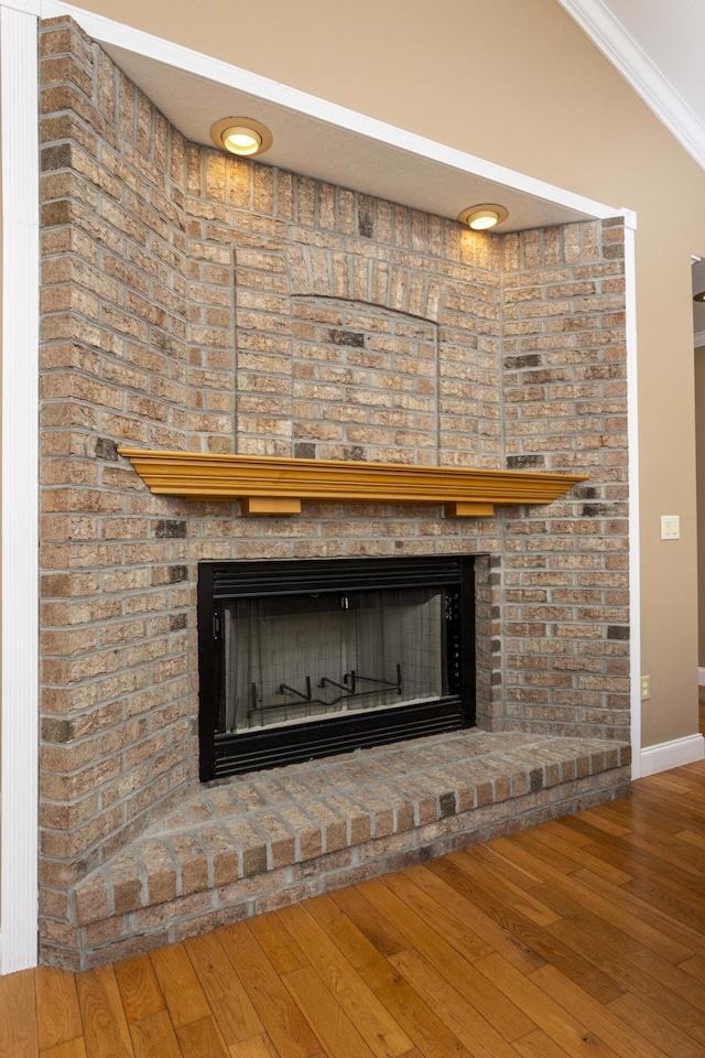 room details featuring hardwood / wood-style flooring, crown molding, and a brick fireplace