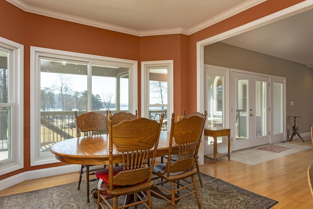 dining space featuring french doors, ornamental molding, and light hardwood / wood-style flooring