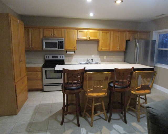 kitchen featuring appliances with stainless steel finishes, a breakfast bar, sink, and light tile patterned floors