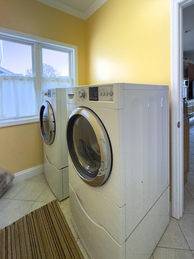 laundry area featuring separate washer and dryer, light tile patterned floors, and crown molding