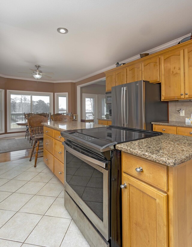 kitchen featuring a wealth of natural light, light tile patterned flooring, ornamental molding, and appliances with stainless steel finishes