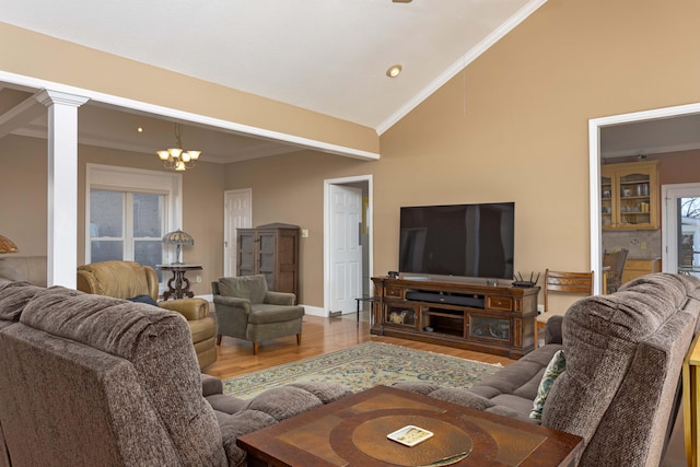 living room with hardwood / wood-style floors, decorative columns, ornamental molding, vaulted ceiling, and a chandelier