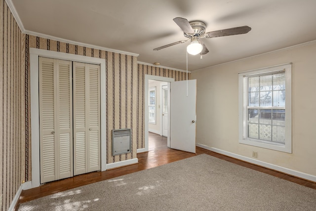 unfurnished bedroom with a closet, ornamental molding, heating unit, and ceiling fan