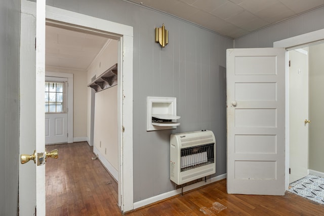 hall with heating unit, wood-type flooring, and ornamental molding