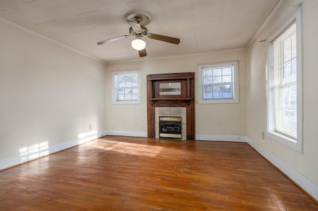 unfurnished living room featuring ceiling fan, hardwood / wood-style flooring, heating unit, crown molding, and a tiled fireplace