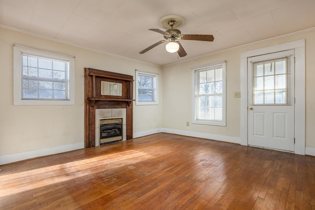 unfurnished living room with ceiling fan, ornamental molding, hardwood / wood-style floors, and a tile fireplace