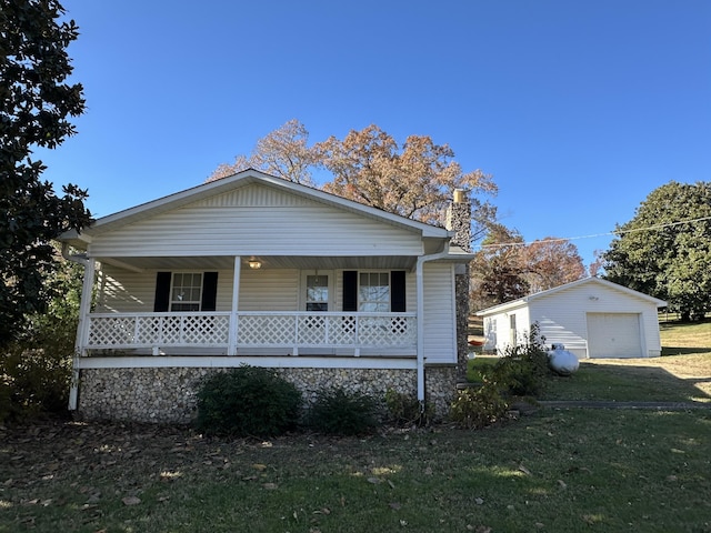 view of front of house with a front lawn, covered porch, an outdoor structure, and a garage